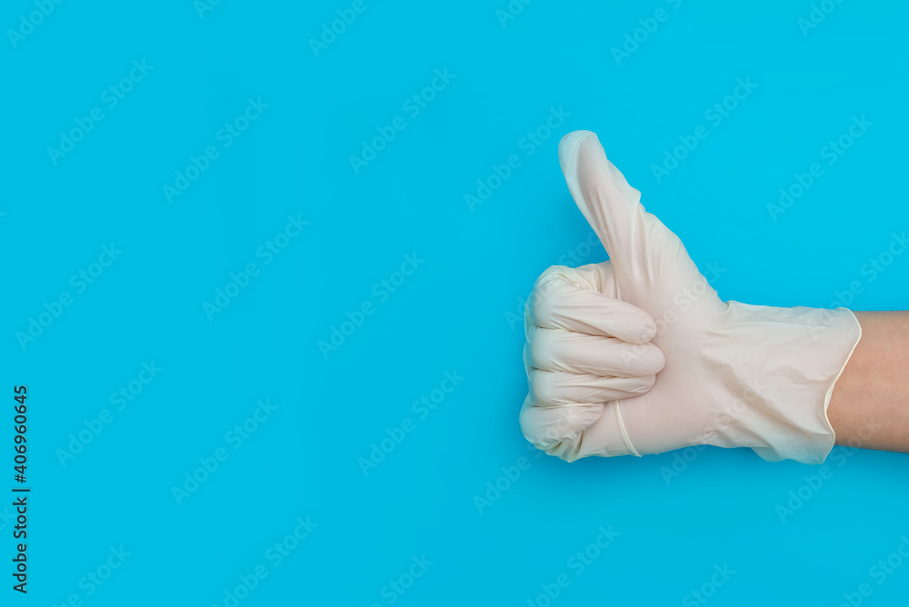 thumbs up, super sign, hands close-up in rubber gloves on blue background copy space, wearing medical gloves