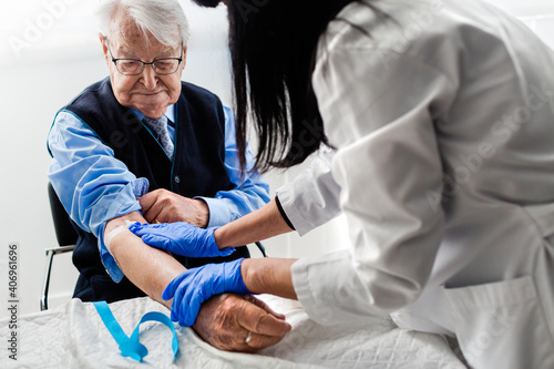 Nurse drawing blood from an elderly man in his home. Home care.