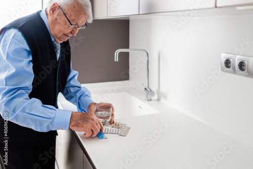 Elderly man taking pills with a glass of water