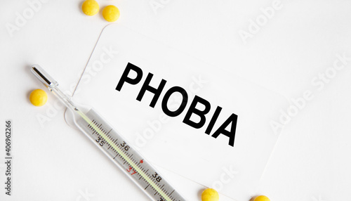 On the business card the text of PHOBIA, next to the thermometer and yellow tablets.