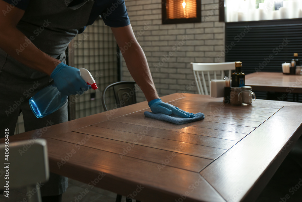 Waiter in gloves disinfecting table at cafe, closeup Waiter in gloves disinfecting table at cafe, closeup
