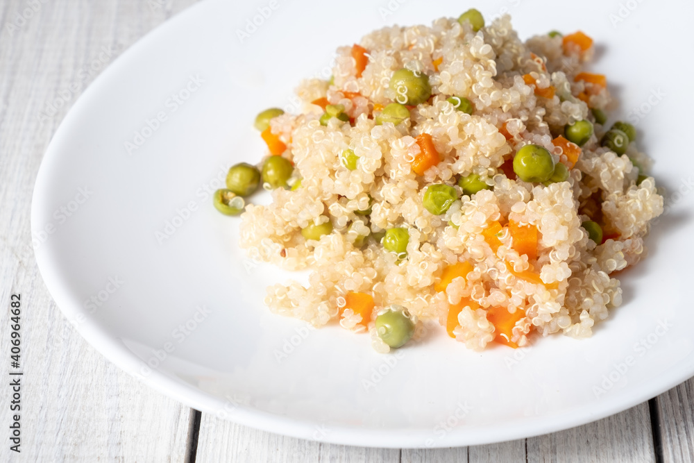 Quinoa porridge with vegetables and avocado in a white flat plate on a wooden board. Superfoods concept and top view. Quinoa porridge with vegetables and avocado in a white flat plate on a wooden board. Superfoods concept and top view.