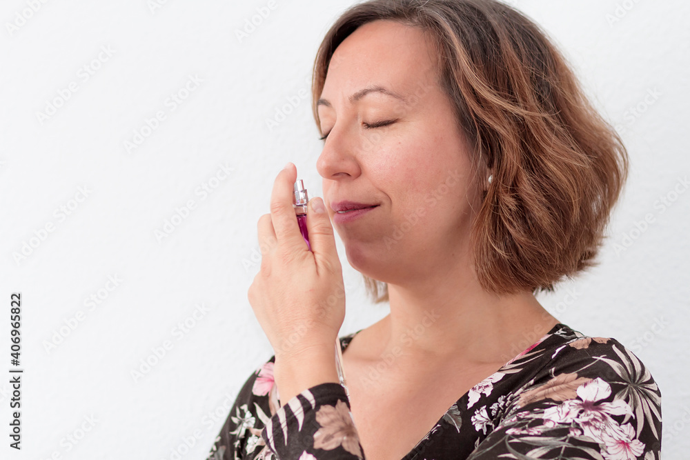 A woman smelling and applying a perfume A woman smelling and applying a perfume
