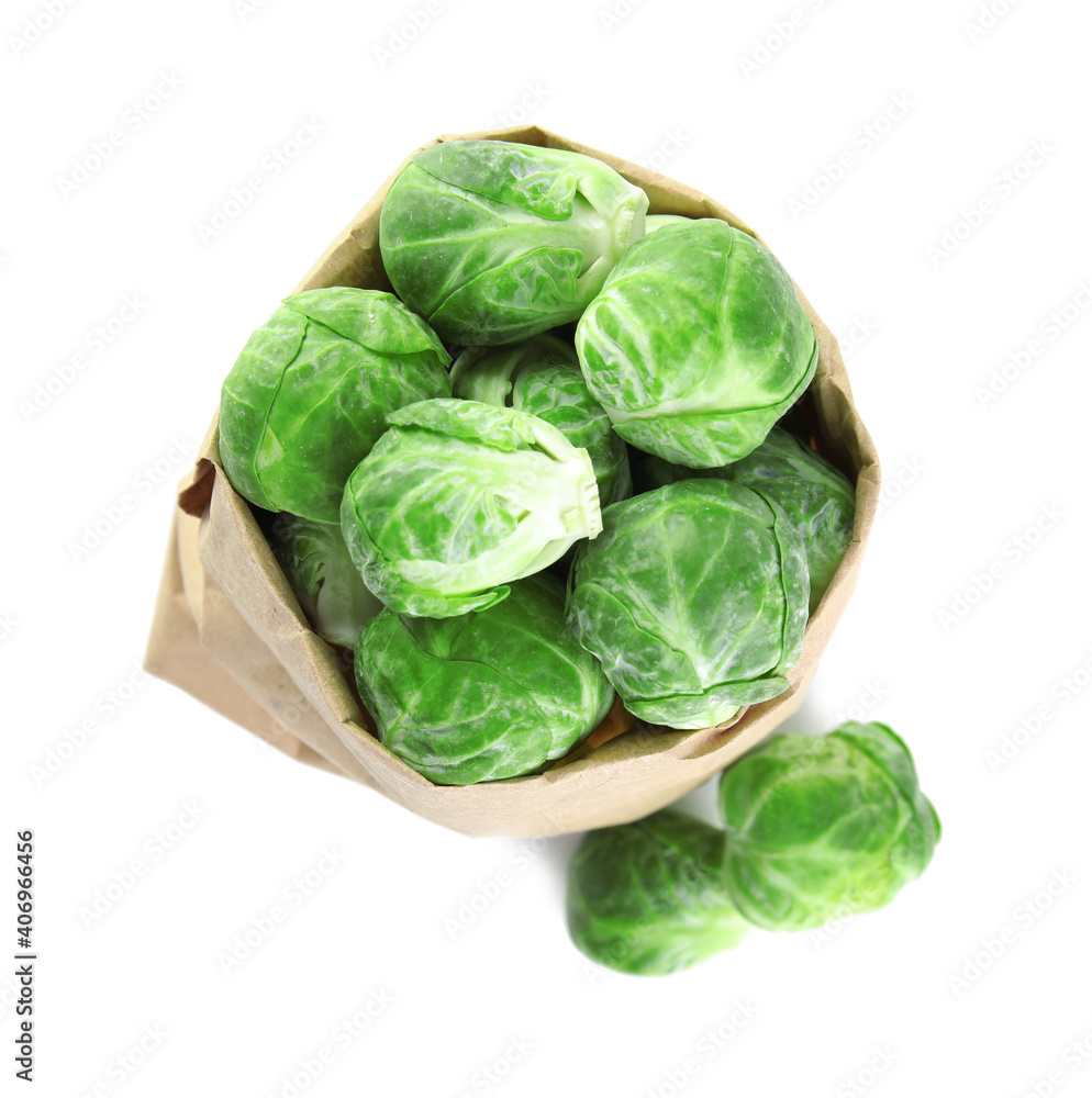 Fototapeta premium Fresh Brussels sprouts in paper bag on white background, top view