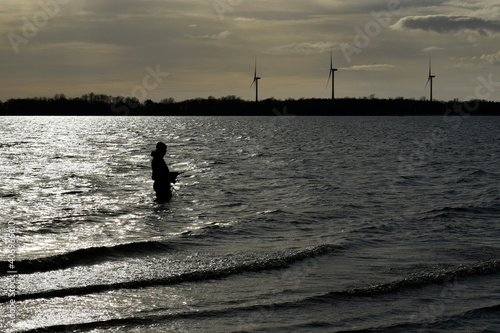 Solo flyfisherman wading while fly fishing in winter at Anglian waters Grafham Water in Bedfordshire.