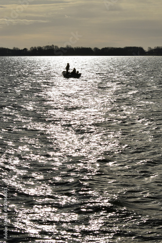 Two men on a small rowing boat with onboard motor, fishing for trout on Grafham Water, Bedfordshire, UK in December. photo