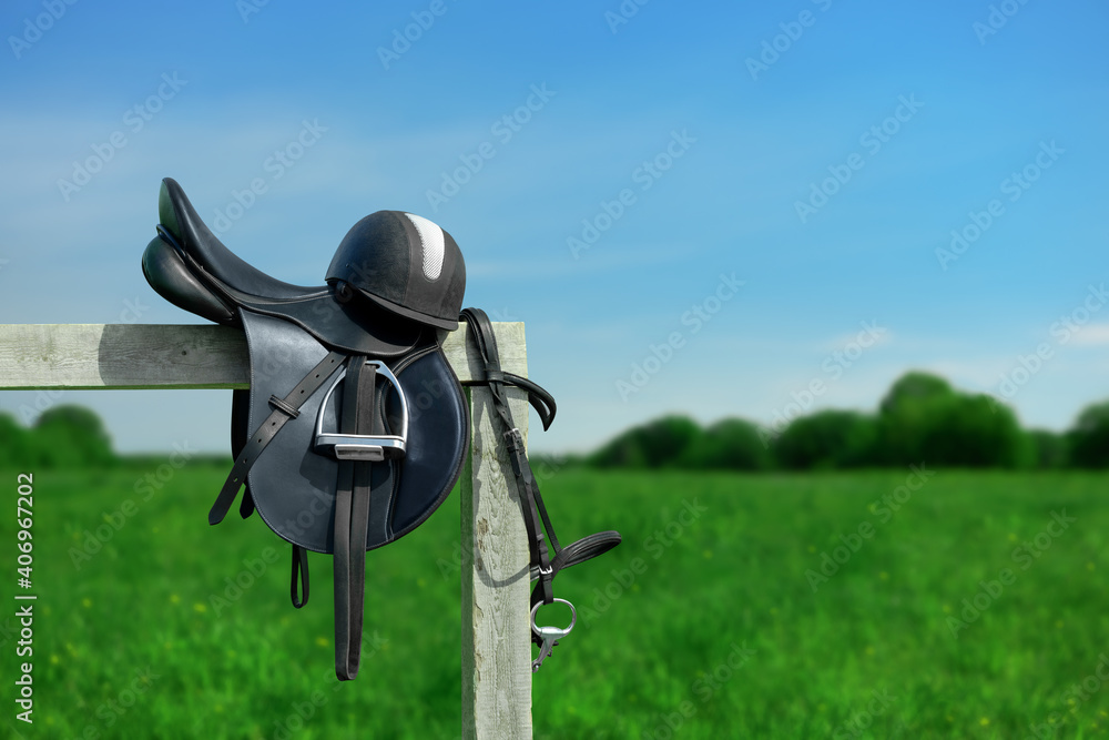 The bridle, the horse saddle and the riding helmet are on the wooden