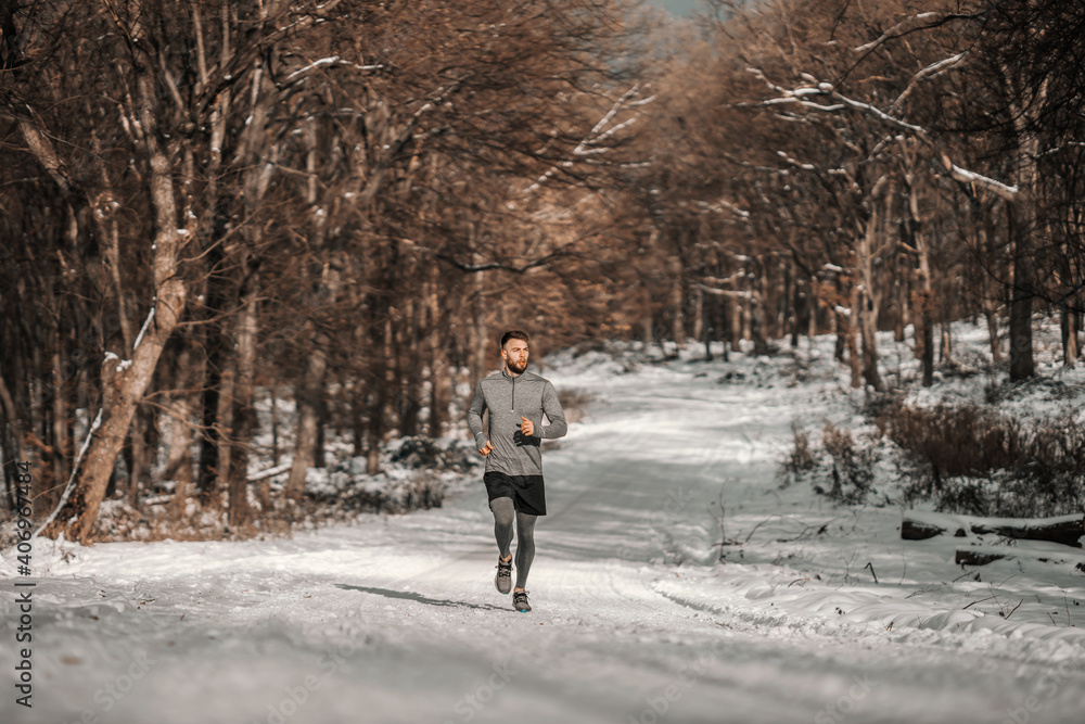Runner running in forest at snowy winter day. Winter fitness, sporty lifestyle, healthy life