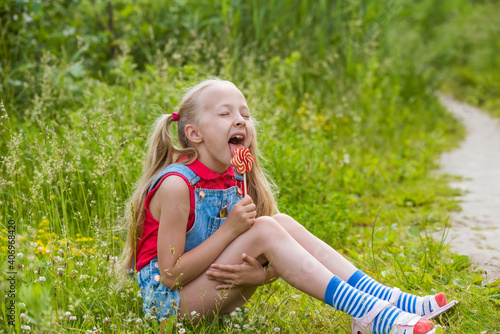 Blonde little girl with long hair and candy on a stick