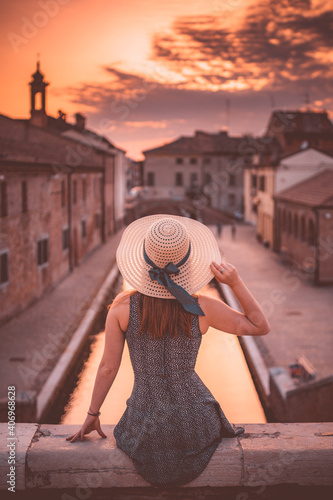 ragazza con cappello che guarda tramonto a comacchio photo