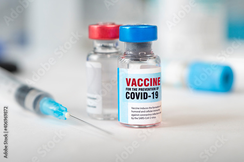 Two bottles of covid 19 coronavirus vaccine and a syringe on white table. The medical conception of combating the covid-19 pandemic.
