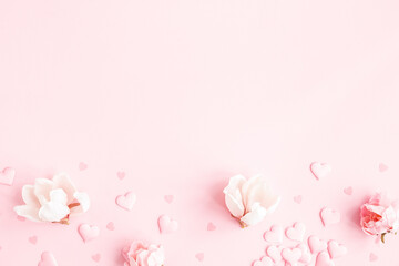 Valentine's Day background. Frame made of pink flowers, hearts on pastel pink background. Valentines day concept. Flat lay, top view, copy space