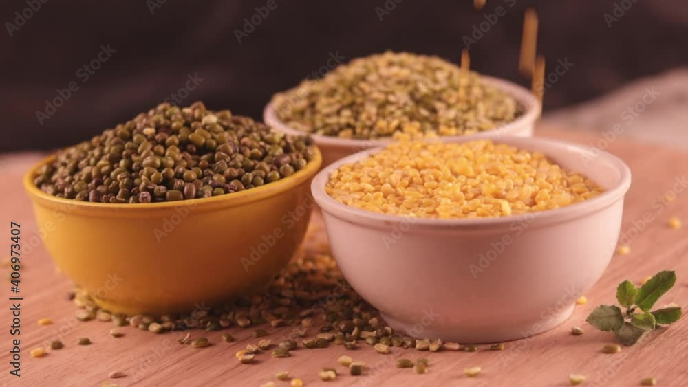 Falling Yellow moong dal, Indian pulse, yellow mong dal and green Moong bean with green mung daal on wooden table, healthy lentil pulse bean on table,falling moong dal on white bowl Falling Yellow moong dal, Indian pulse, yellow mong dal and green Moong bean with green mung daal on wooden table, healthy lentil pulse bean on table,falling moong dal on white bowl