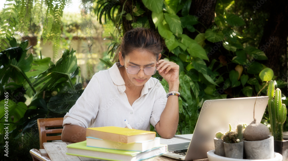 woman tired of work tired sleepy young woman sitting at her garden with books in front of laptop computer. Busy schedule in college, workplace, sleep deprivation concept woman tired of work tired sleepy young woman sitting at her garden with books in front of laptop computer. Busy schedule in college, workplace, sleep deprivation concept