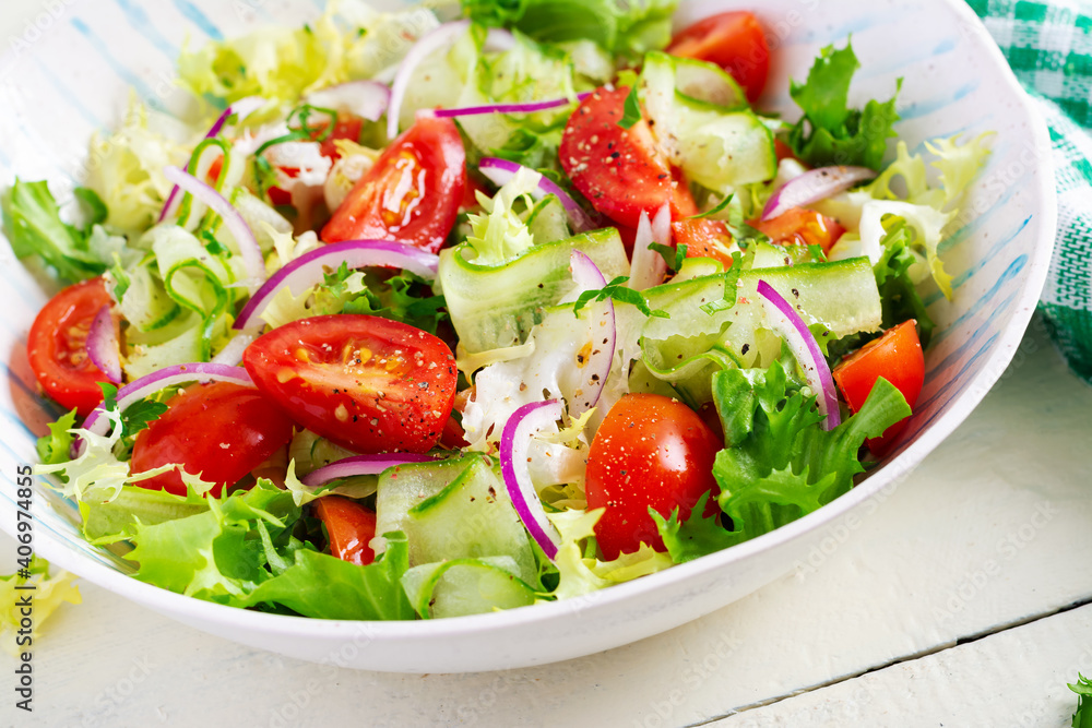Fresh tomatoes with cucumber, lettuce, red onion and spices in a white bowl. Concept healthy appetizer. White wooden background. Fresh tomatoes with cucumber, lettuce, red onion and spices in a white bowl. Concept healthy appetizer. White wooden background.