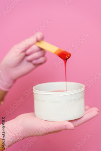 Girl cosmetician in pink medical gloves with pasta for shugaring