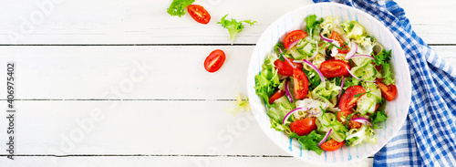 Fresh tomatoes with cucumber, lettuce, red onion and spices in a white bowl.  Concept healthy appetizer. White wooden background. Top view, overhead, copy space