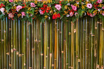 flowers with fern leaf decorate on wall of bamboo stick.