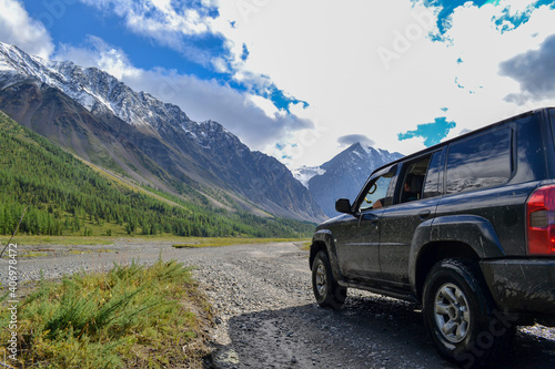 Off-road SUV car with Aktru mountain valley and glacier background. Adventure travel concept. Adventure tourism. Nature landscape. Overland 4x4 journey concept. © Adil