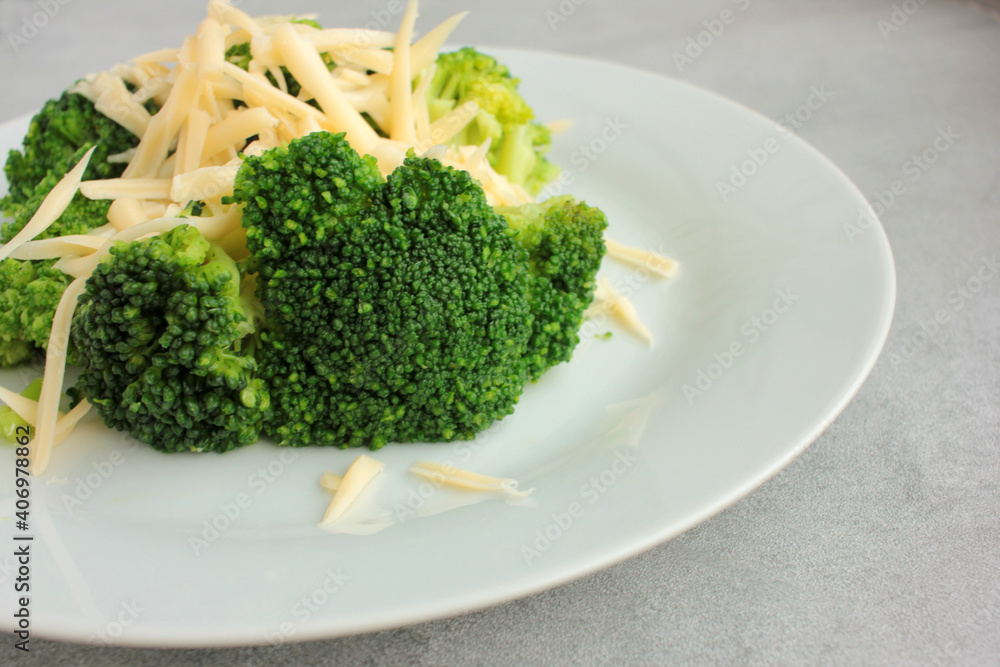 Broccoli with grated cheese on a plate. Overhead view. Close-up Broccoli with grated cheese on a plate. Overhead view. Close-up