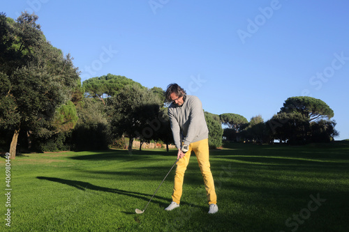 adult man in a golf iron swing