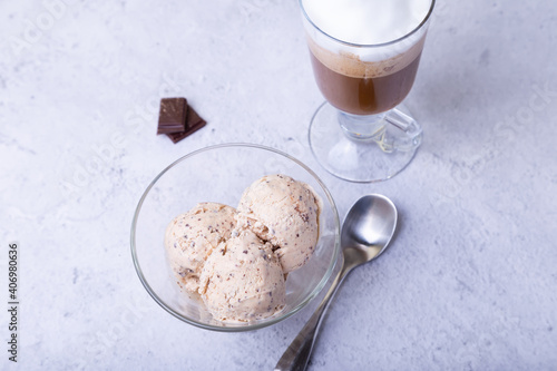 Homemade ice cream with chocolate chips in a bowl. Three balls of ice cream and a cup with coffee. Close-up. photo