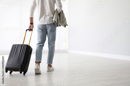 Man with black travel suitcase in airport. Space for text