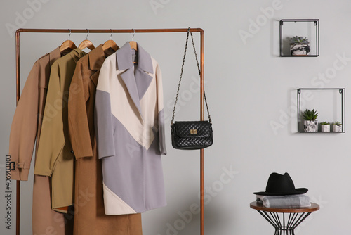 Different warm coats on rack in stylish room interior photo