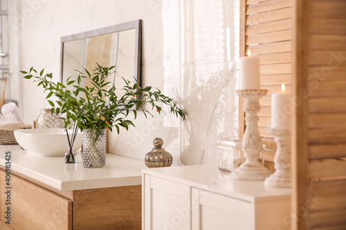 Vase with beautiful branches near vessel sink in bathroom. Interior design