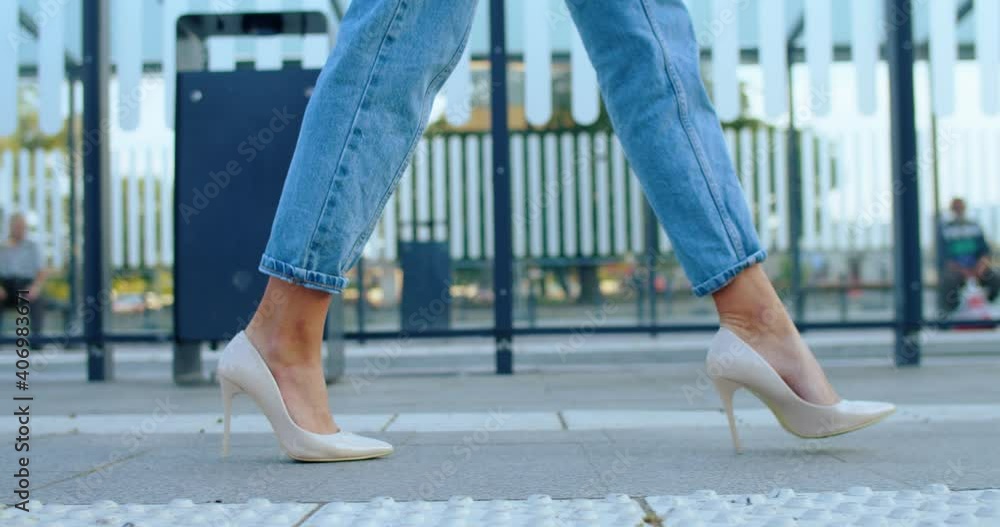 Close up of young womans legs in jeans and in high heels walking outdoor. Pretty female tourist strolling at bus and tram stop in modern beautiful city. Train station. Travel, tourism concept Close up of young womans legs in jeans and in high heels walking outdoor. Pretty female tourist strolling at bus and tram stop in modern beautiful city. Train station. Travel, tourism concept