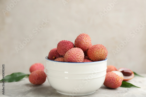 Fresh ripe lychee fruits in bowl on light grey table