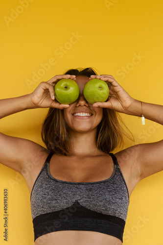 healthy, smiling woman putting the apples in her eyes on a yellow background Health, diet, eating, slimming © Paula