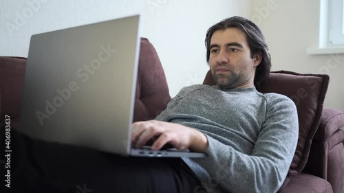 caucasian  millennial man sit relax on couch using modern laptop browsing unlimited wireless internet, young male freelancer work on computer typing texting from home, technology concept photo