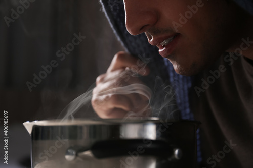 Man with plaid doing inhalation above saucepot, closeup