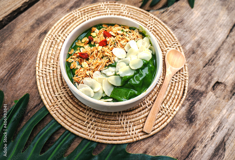 Top view Breakfast Detox Green Smoothie bowls  from Green tea and Spinach with fruits, nuts, seeds and homemade granola and  for healthy vegan on the table.