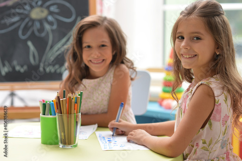 Two cute little girls drawing with pencils photo