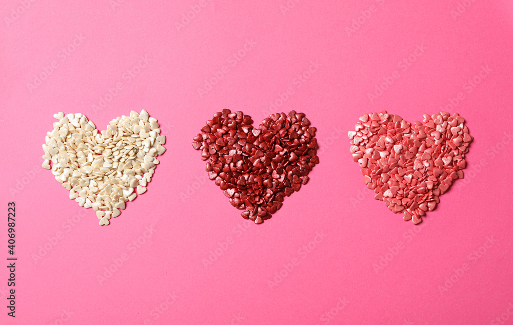Hearts made with sprinkles on pink background, flat lay