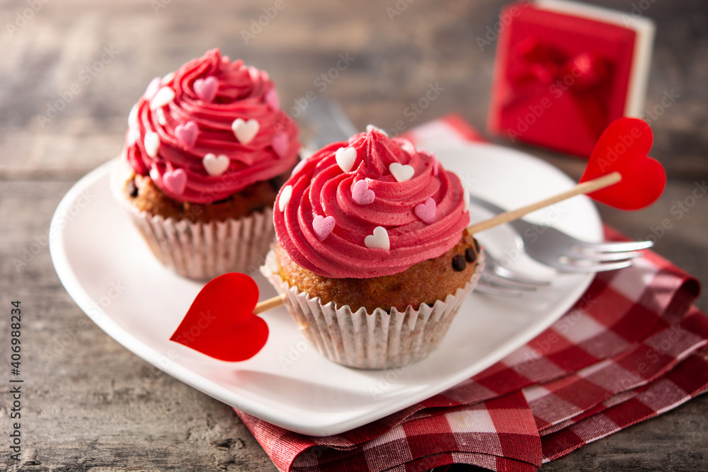 Cupcake decorated with sugar hearts and a cupid arrow for Valentine's Day on wooden table Cupcake decorated with sugar hearts and a cupid arrow for Valentine's Day on wooden table