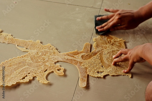Closeup Of Man's Hand Sanding The Shadow Puppet Or Wayang Kulit Before Coloring
