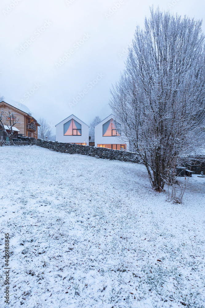 Modern white house with large windows surronded by nature, snow and fog