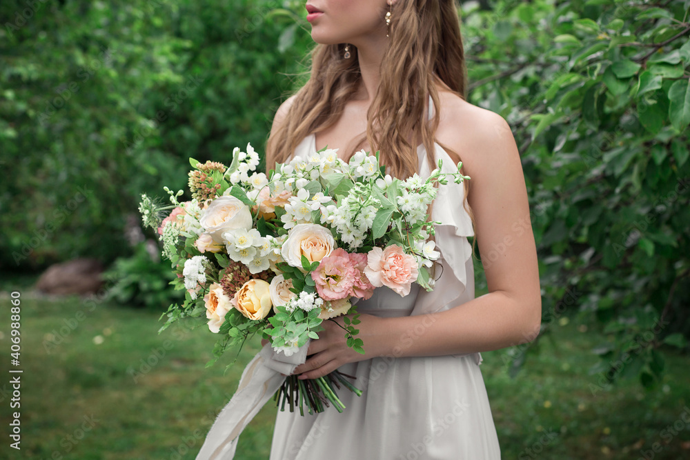 A girl in a white dress holds a delicate bouquet of the bride in her hands A girl in a white dress holds a delicate bouquet of the bride in her hands