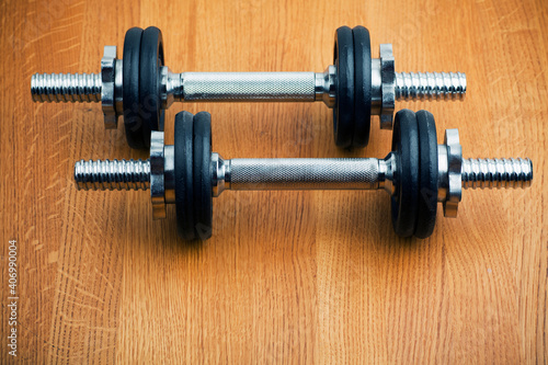 Studio photo of two dumbbells on wooden background.