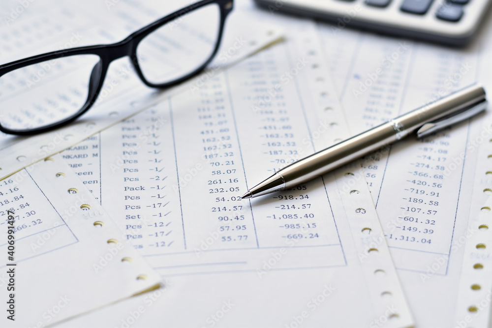 Elegant stainless steel pens on a pile of paper documents with blurred glasses is background. Elegant stainless steel pens on a pile of paper documents with blurred glasses is background.