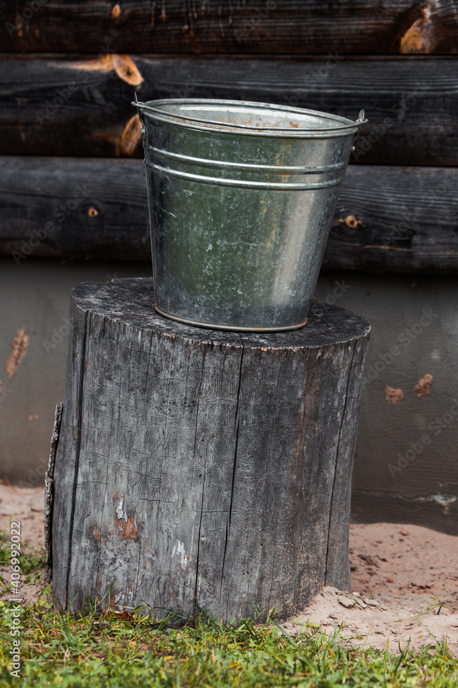 Metal water bucket on stumped wood with beautiful background. Metal water bucket on stumped wood with beautiful background.