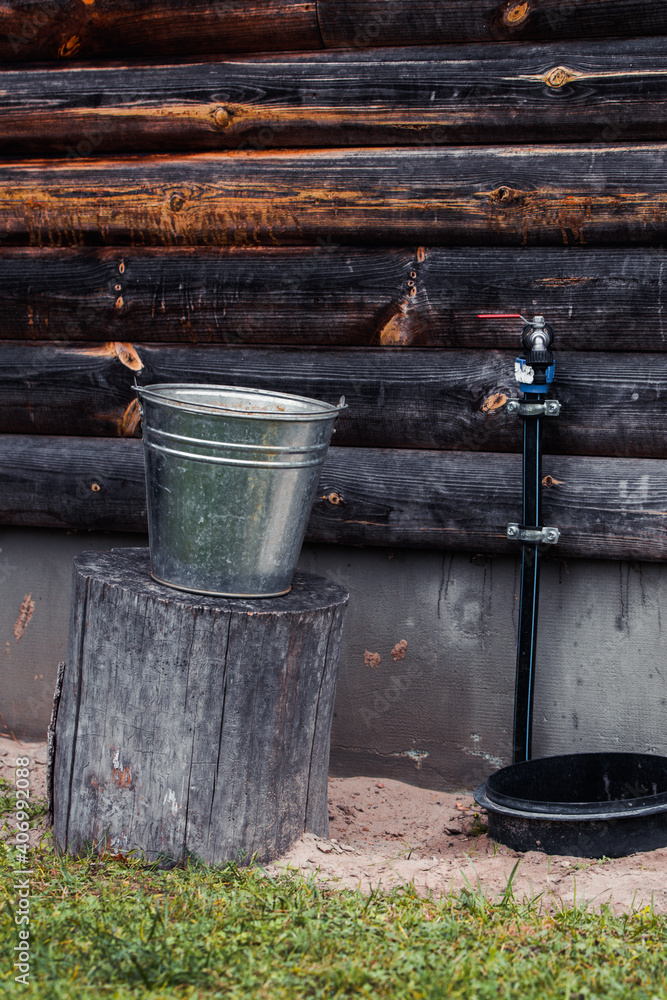 Bucket on stumped wood with water tap in backyard. Bucket on stumped wood with water tap in backyard.