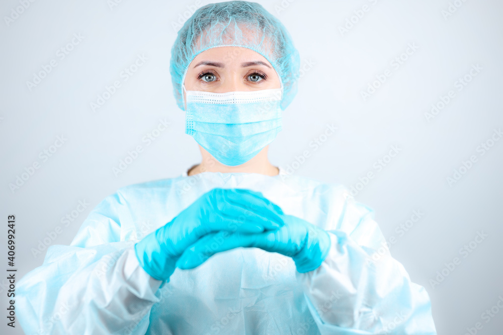 a nurse in a medical gown and mask folded her hands in front of her a nurse in a medical gown and mask folded her hands in front of her
