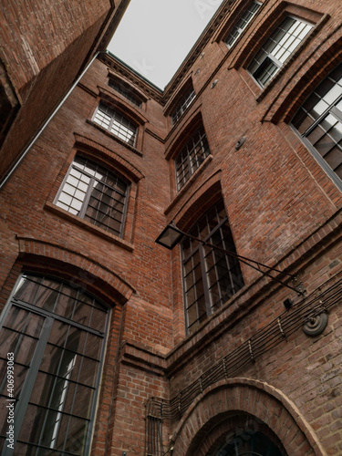 Upward view to high building red brick wall with big windows