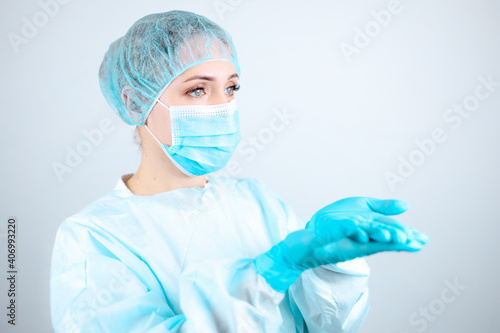 a nurse in a medical gown, mask and protective gloves stands with her palms outstretched
