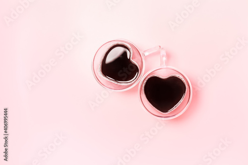 Two cute heart shaped coffee mugs on pink background with copy space. Valentines Day flatlay composition.