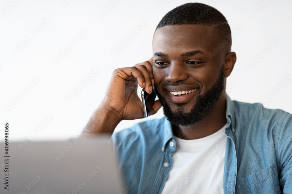 Closeup Portrait Of Smiling Black Man Talking On Cellphone And Using Laptop Closeup Portrait Of Smiling Black Man Talking On Cellphone And Using Laptop